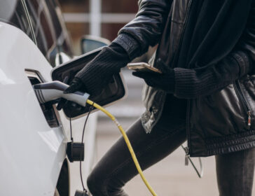 Woman charging electro car at the street